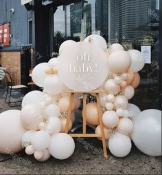 a sign that says on baby in front of some white and gold balloons with the words on it