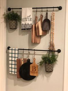 kitchen utensils hanging on the wall with potted plants and wooden cutting boards