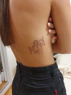 the back of a woman's stomach with a small tattoo on her left side