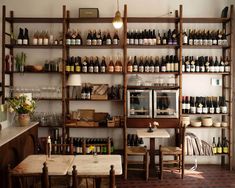 a room filled with lots of bottles of wine on shelves next to tables and chairs