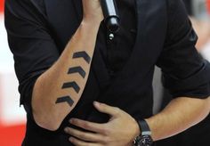 a man holding a microphone with an arrow tattoo on his arm