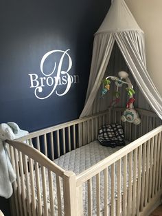 a white crib in a room with blue walls and a name on the wall