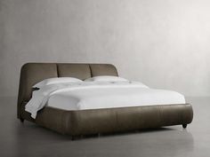 a bed that is made up and has white sheets on top of it, in a room with gray walls