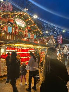 many people are walking around in front of the christmas decorations and lights on display at an amusement park