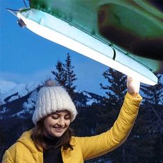 a woman in yellow jacket holding up an umbrella over her head with mountains in the background