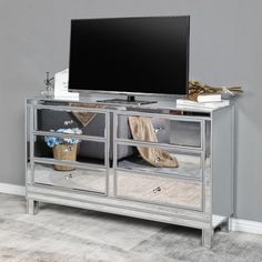 an entertainment center with mirrored drawers and a flat screen tv mounted on the sideboard