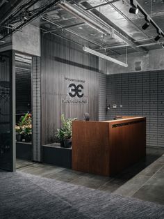 an office with a wooden desk and metal partitions on the wall, along with plants