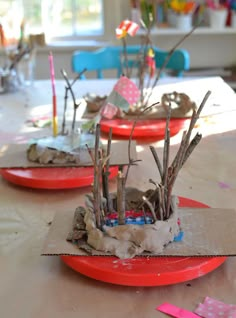 three red plates with branches in them sitting on a table covered in paper mache