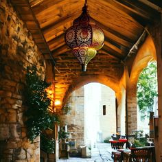 the inside of a restaurant with tables and lamps hanging from it's ceilings