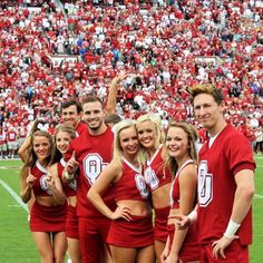 a group of cheerleaders posing for a photo in front of a stadium full of people