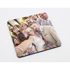 a couple taking a photo with their wedding party pictures on the mouse pad that they are holding