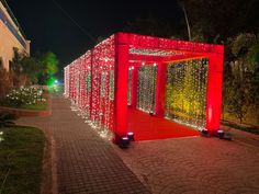 a red structure covered in christmas lights on the side of a road