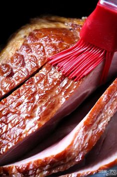 a large piece of meat being cooked with a red spatula on top of it