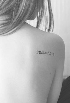 the back of a woman's shoulder with an inscription on it that reads imagine