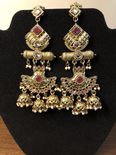 Red Bollywood Jhumkas With Intricate Design, Red Kundan Jhumkas With Intricate Design, Bollywood Style Ruby Jhumkas With Latkans, Bollywood Ruby Jhumkas With Latkans, Red Stone Work Temple Jewelry Jhumkas, Ruby Chandelier Earrings For Wedding, Red Cutdana Tikka For Wedding, Bollywood Ruby Jhumkas For Festive Occasions, Bollywood Style Bridal Earrings With Gold And Ruby