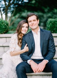 a man and woman sitting next to each other on the steps in front of trees