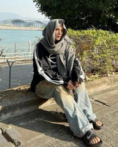 a man sitting on the side of a road next to water