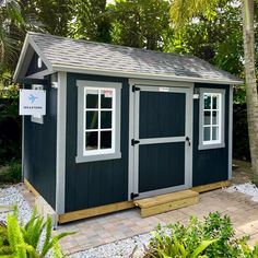 a black and white shed sitting in the middle of a garden