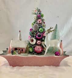 a small christmas tree with ornaments on it and a white horse in the foreground