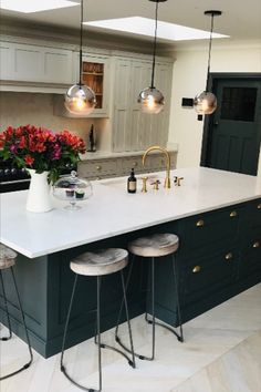 a kitchen island with three stools in front of it and flowers on the counter