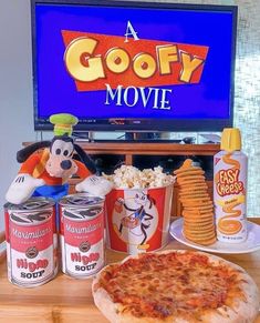 a pizza sitting on top of a wooden table next to two cans of sodas