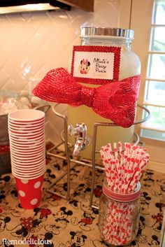 a mickey mouse themed party with red and white paper straws, mason jars, and minnie mouse napkins