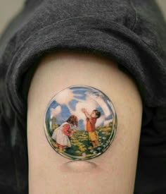 a woman's arm with a small tattoo on it, depicting two children in a field