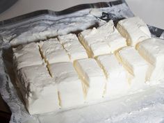 several pieces of white cake sitting on top of a piece of plastic wrapper next to a knife