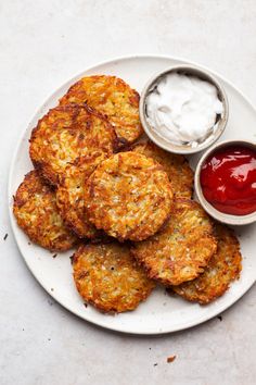 a white plate topped with crab cakes next to ketchup and mayonnaise