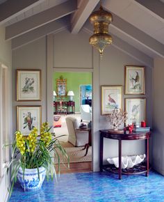 a living room filled with furniture and pictures on the wall next to a blue floor