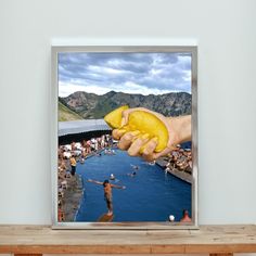 a person holding up a banana in front of a swimming pool with mountains in the background