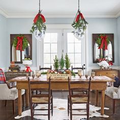 a dining room table decorated for christmas with wreaths and greenery on the windowsill