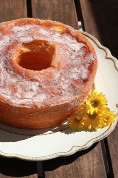 a cake sitting on top of a white plate next to a yellow flower