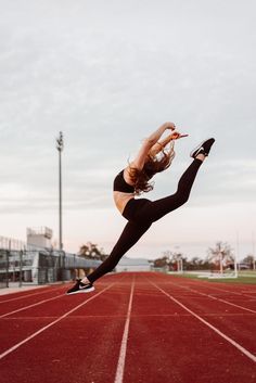 a woman is jumping in the air on a running track with her legs spread out