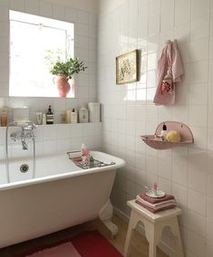 an instagram photo of a bathroom with pink accents and white tiles, including a bathtub