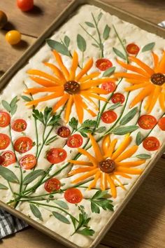 an orange flower is painted on the side of a cookie sheet with tomatoes and green leaves