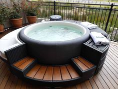 an inflatable hot tub sitting on top of a wooden deck next to potted plants