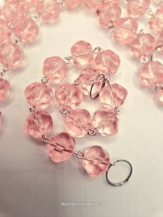 a close up of a pink necklace on a white surface