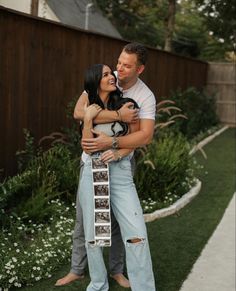 a man and woman hugging each other in front of a fence