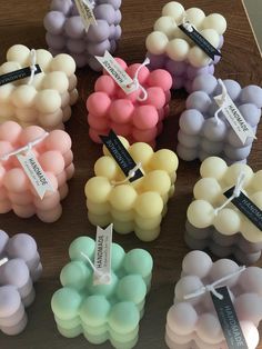 many different colored candles with tags on them sitting next to each other in front of a wooden table