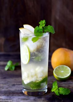 two glasses filled with lemonade and mint garnish on top of a wooden table