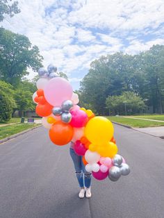 a woman is walking down the street with balloons in her hand and she is holding on to it