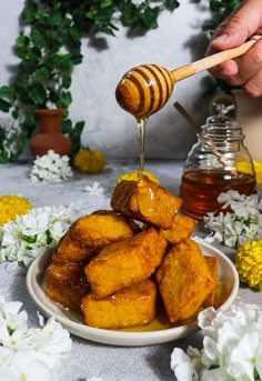 honey being drizzled over fried food on a plate with flowers around it