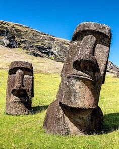 two large statues sitting in the grass next to each other on top of a hill