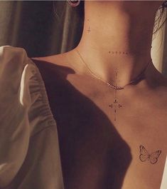 the back of a woman's chest with a cross and butterfly tattoo on it