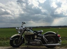 a black and white motorcycle parked on the side of a road in front of a green field