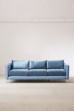 a blue couch sitting on top of a hard wood floor next to a white wall