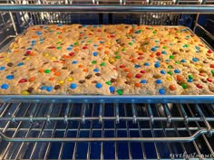 a cookie in an oven with lots of colorful candy on the top and bottom, ready to be baked