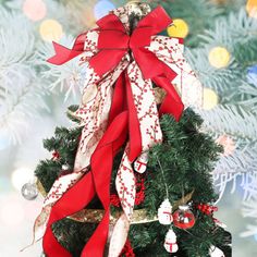 a small christmas tree with red and white ribbons on it's top, decorated with ornaments