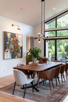 the dining room table is surrounded by modern chairs and an art work on the wall